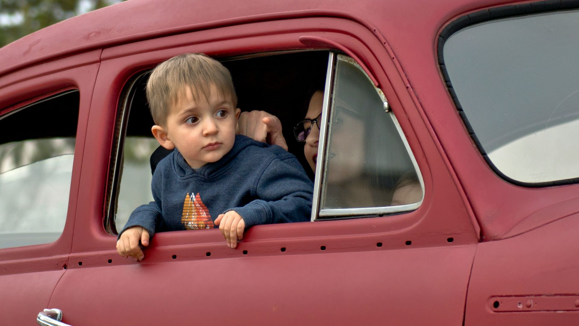 toddler riding on red vehicle