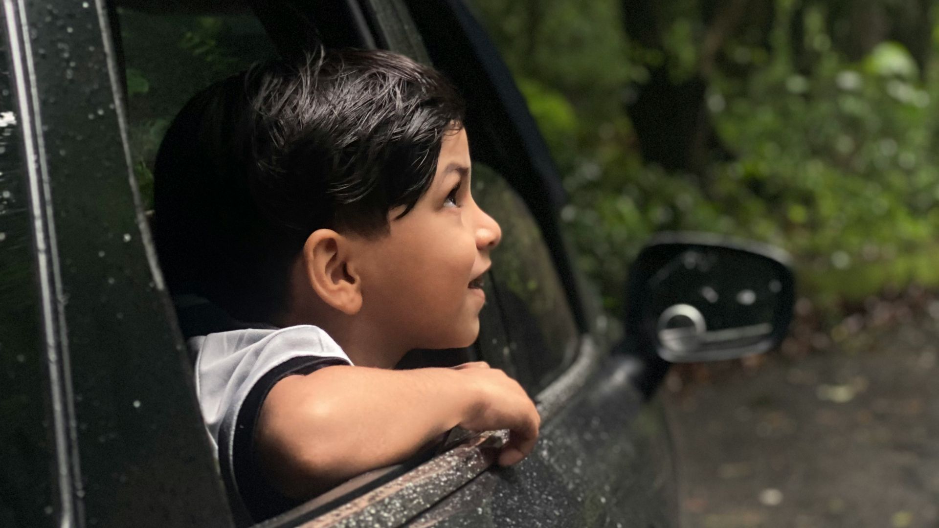 A young boy looking out the window of a car