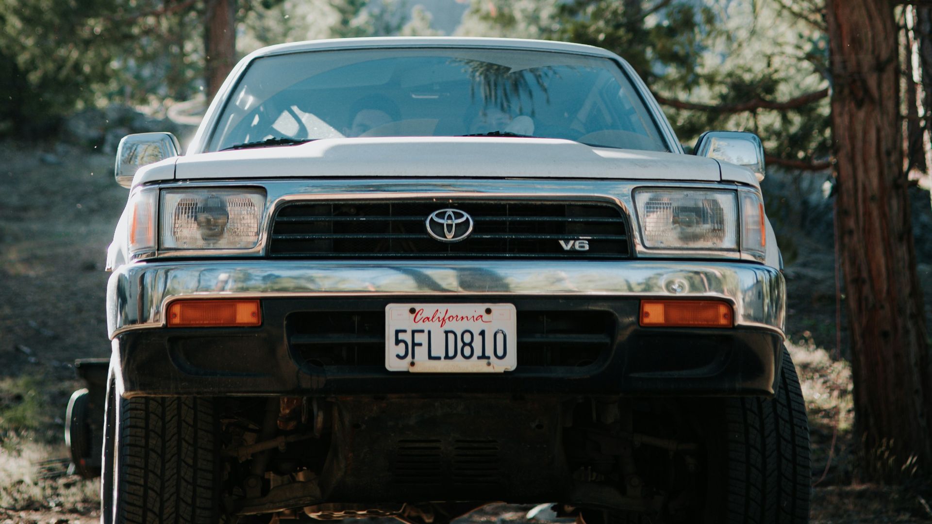 a silver truck parked in the middle of a forest