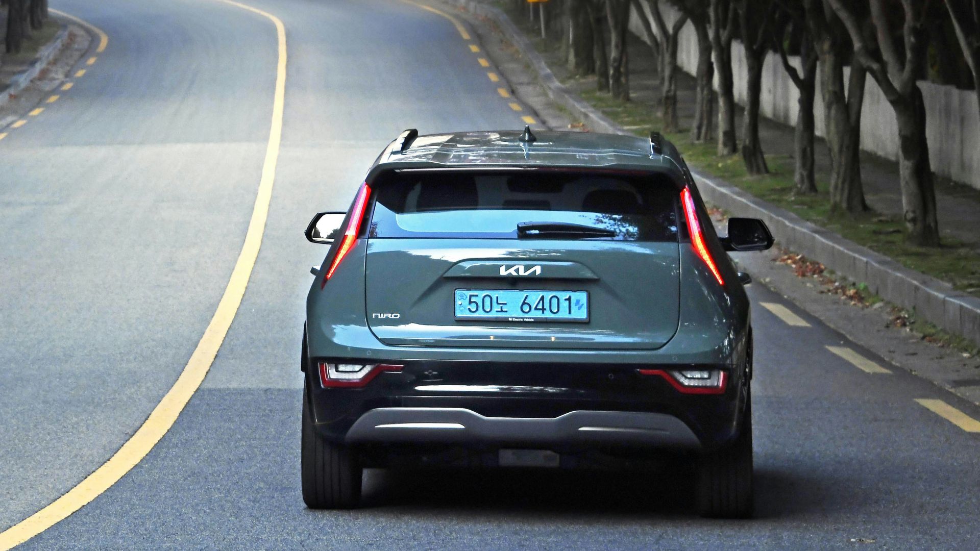 a car driving down a road with trees on either side of it