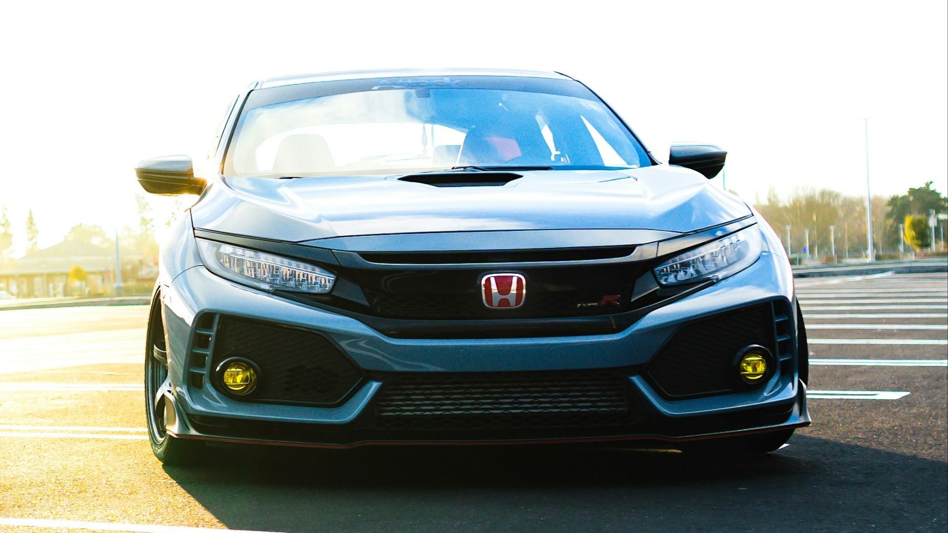 a silver car driving down a street next to a parking lot