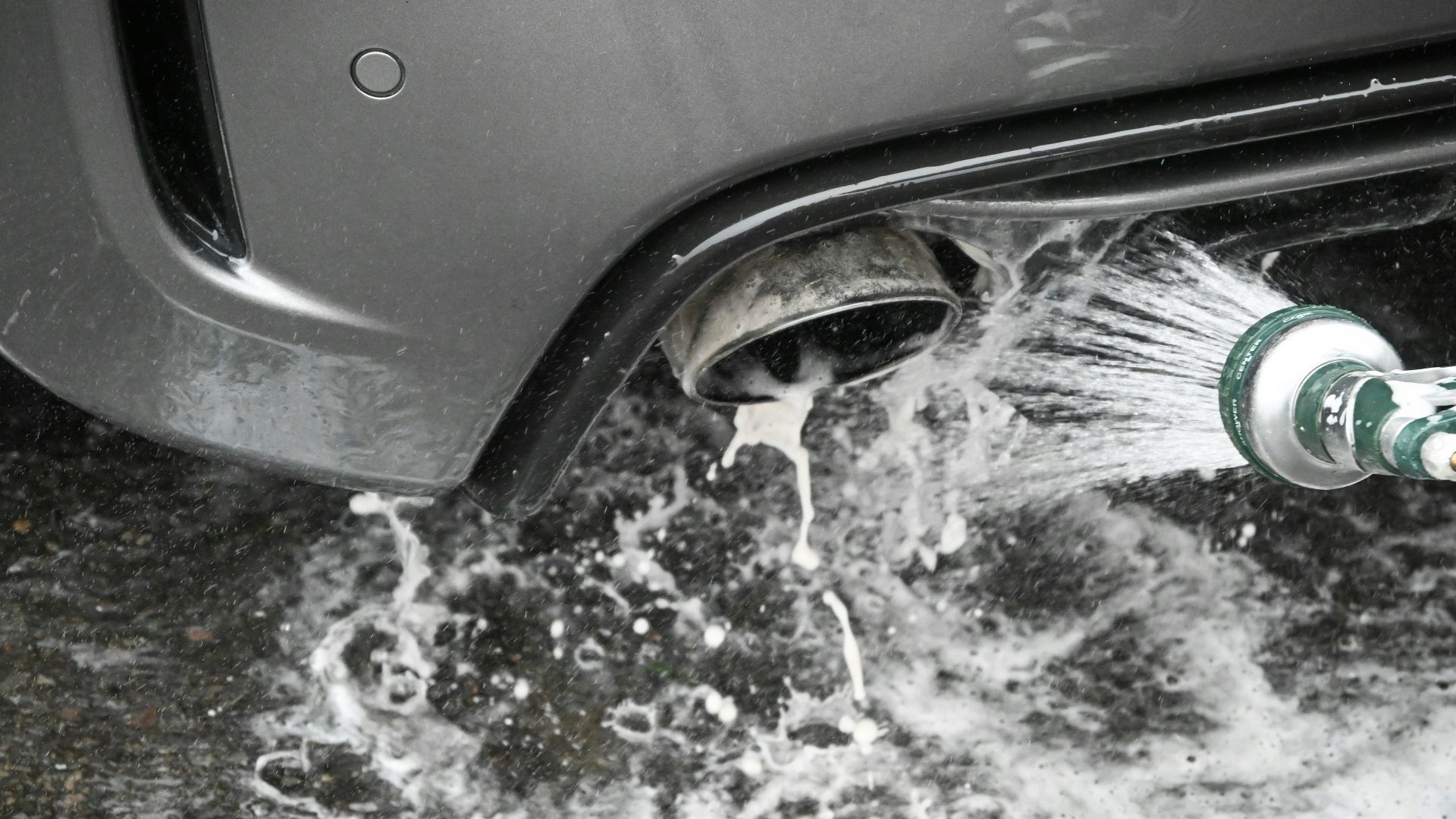 a person is washing a car with a hose
