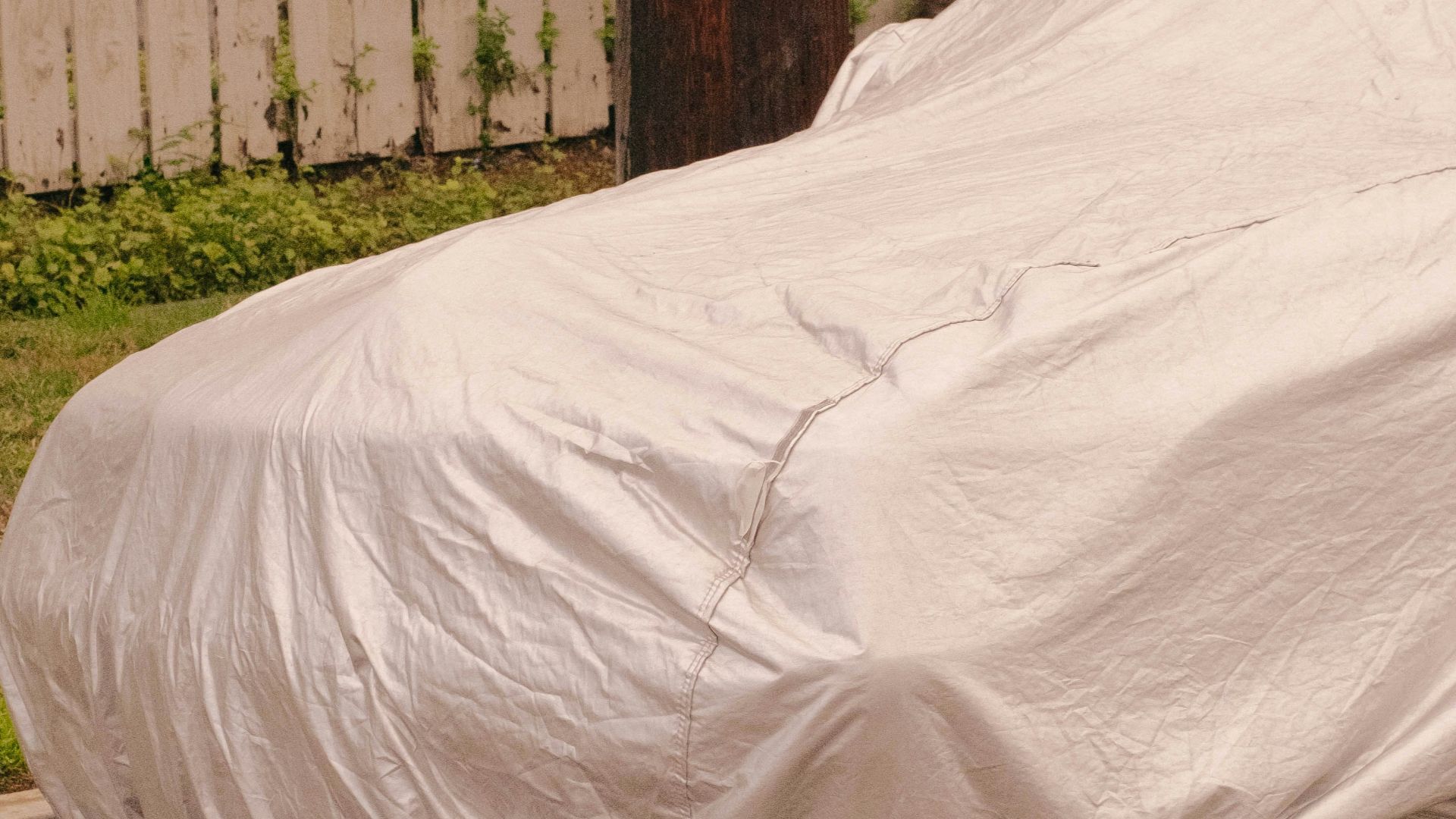 a car covered in a white sheet on the side of the road