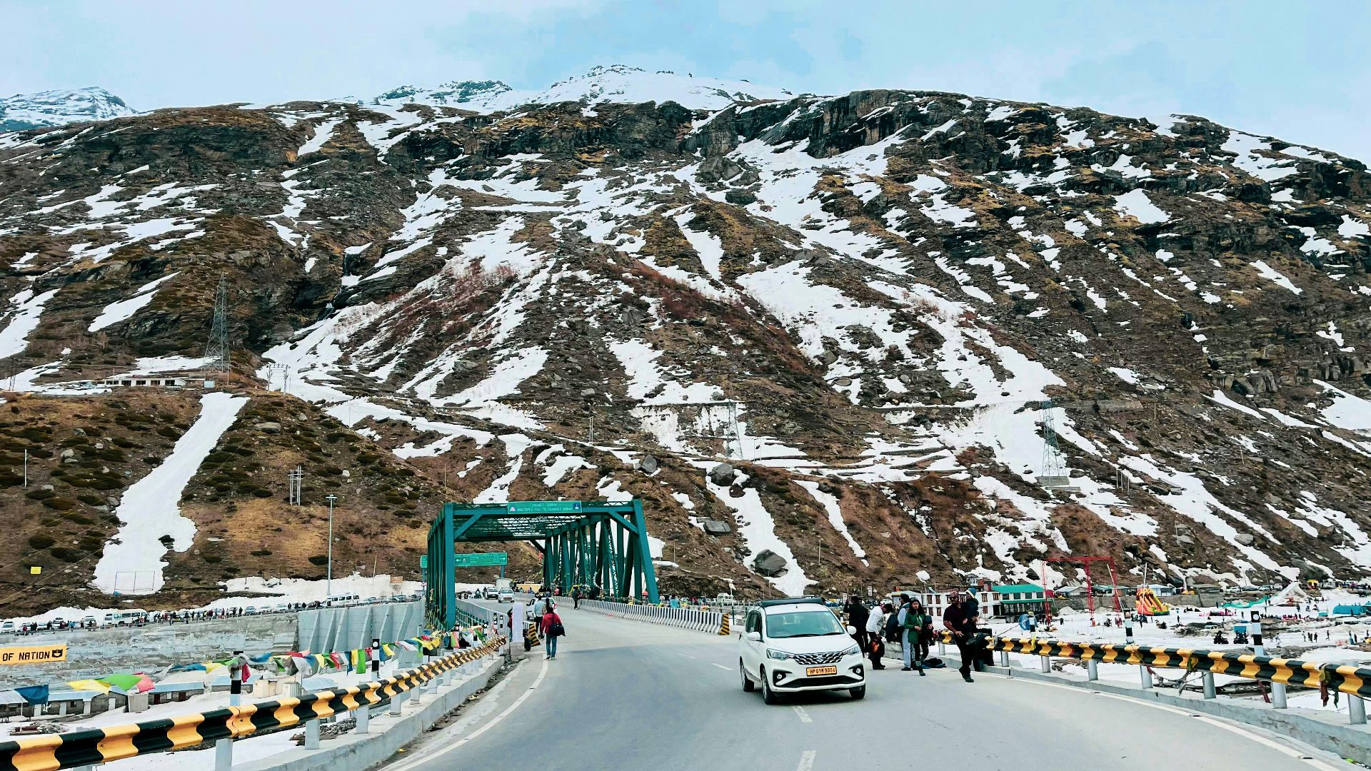 a car driving down a road next to a mountain