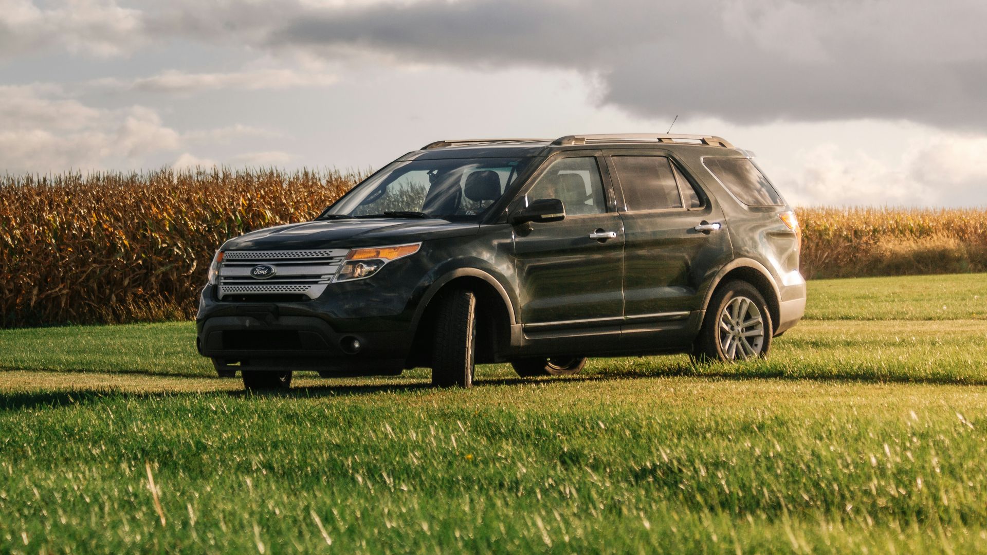a black suv parked in a field of grass
