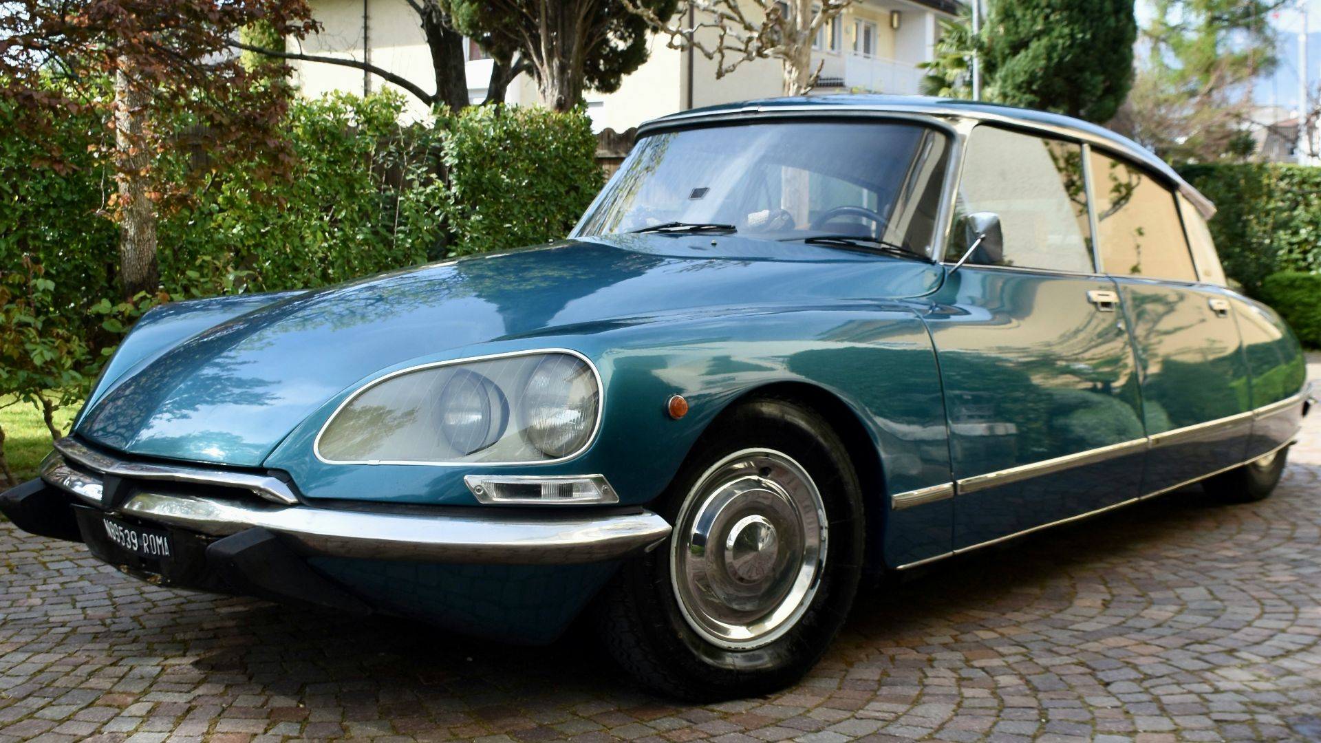a blue car is parked on a cobblestone driveway