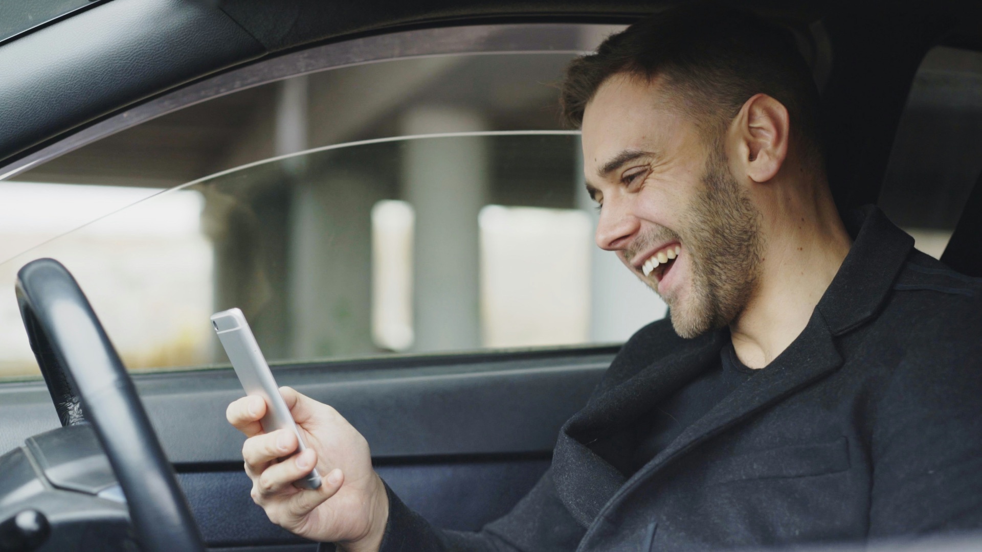 Smiling man looking at his phone in car