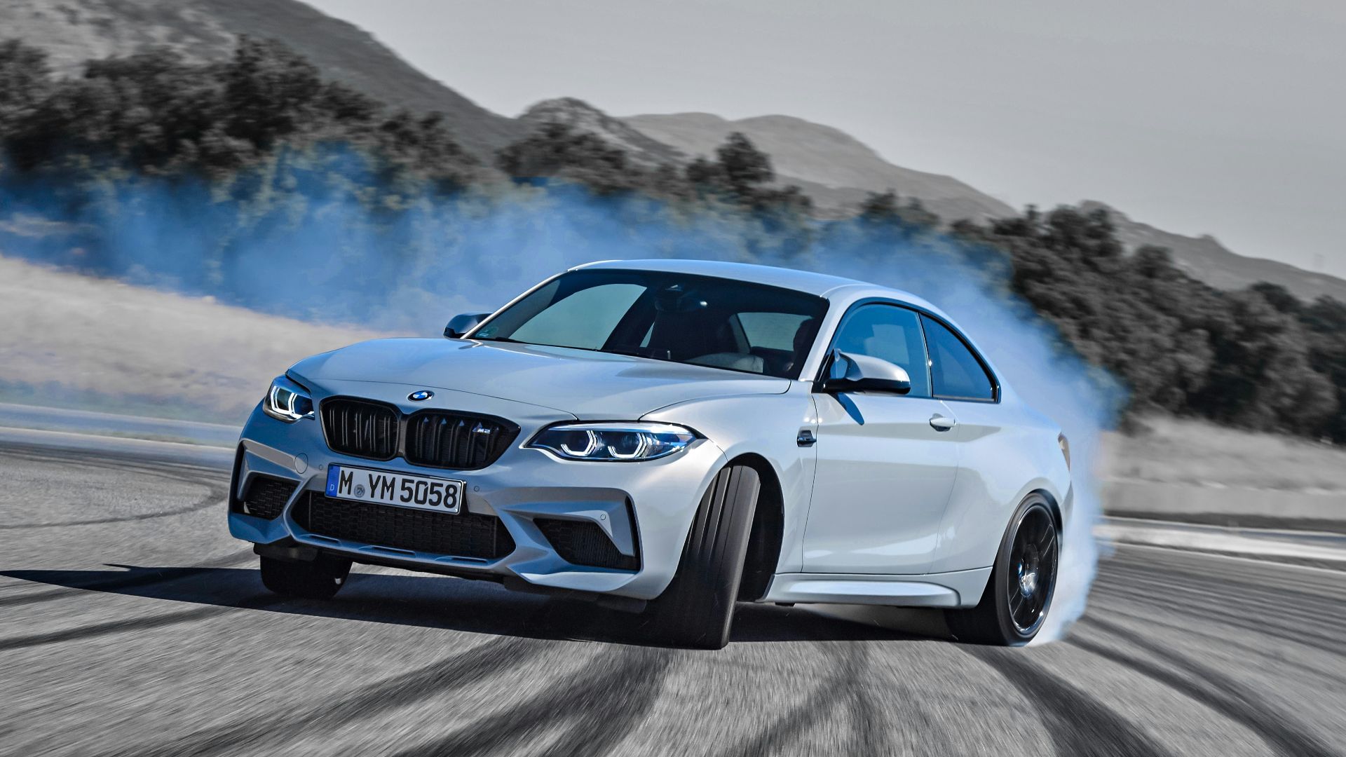 a white bmw car driving down a road