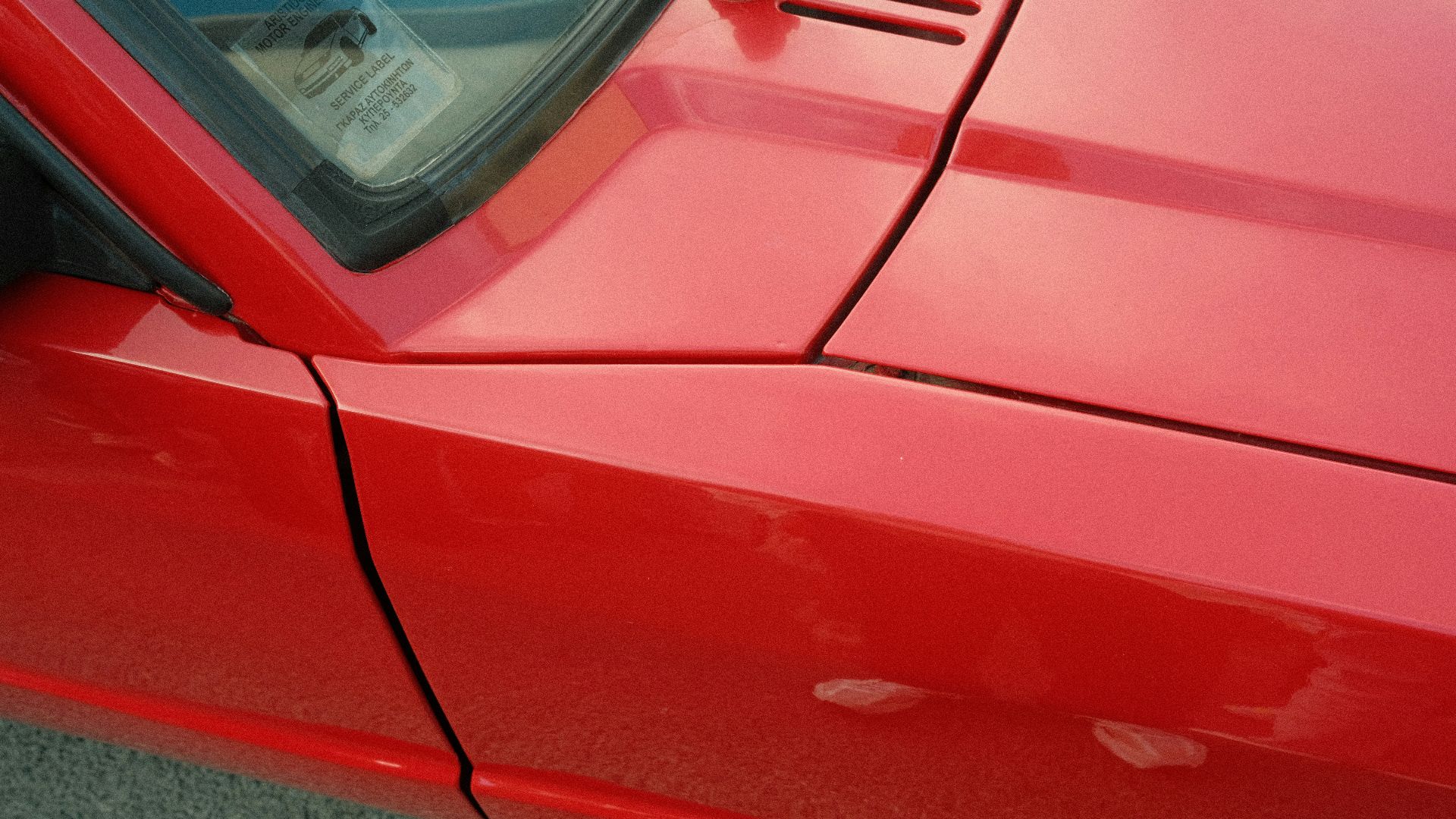 Close-up of a shiny red car's fender and hood.