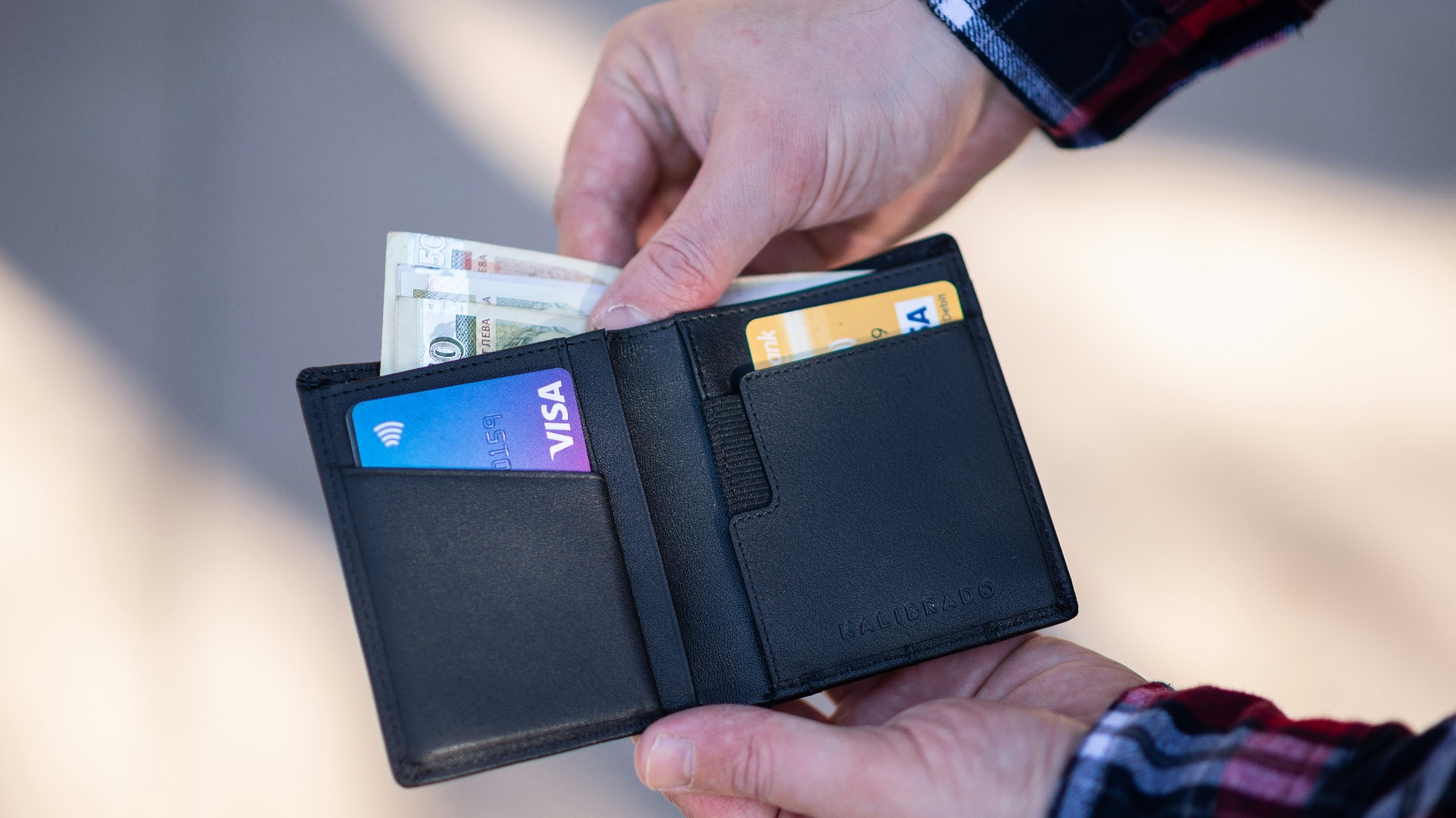 black leather bifold wallet on persons hand