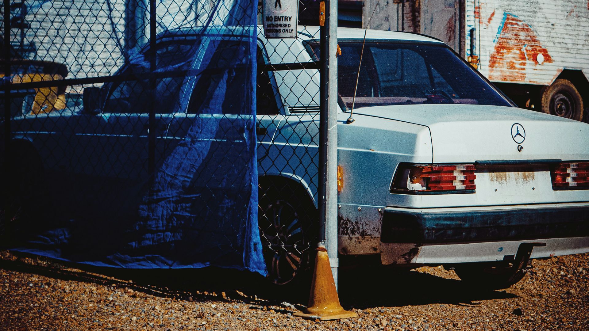 a car parked in front of a fence with a tarp covering it