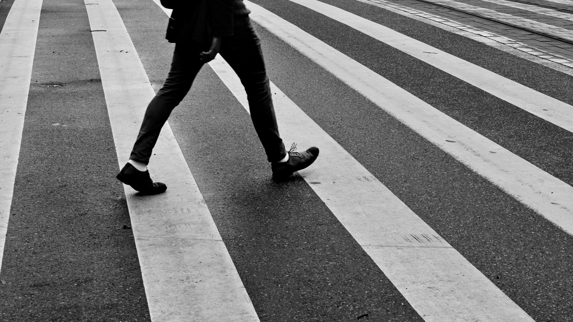 person in black pants and black sneakers walking on pedestrian lane