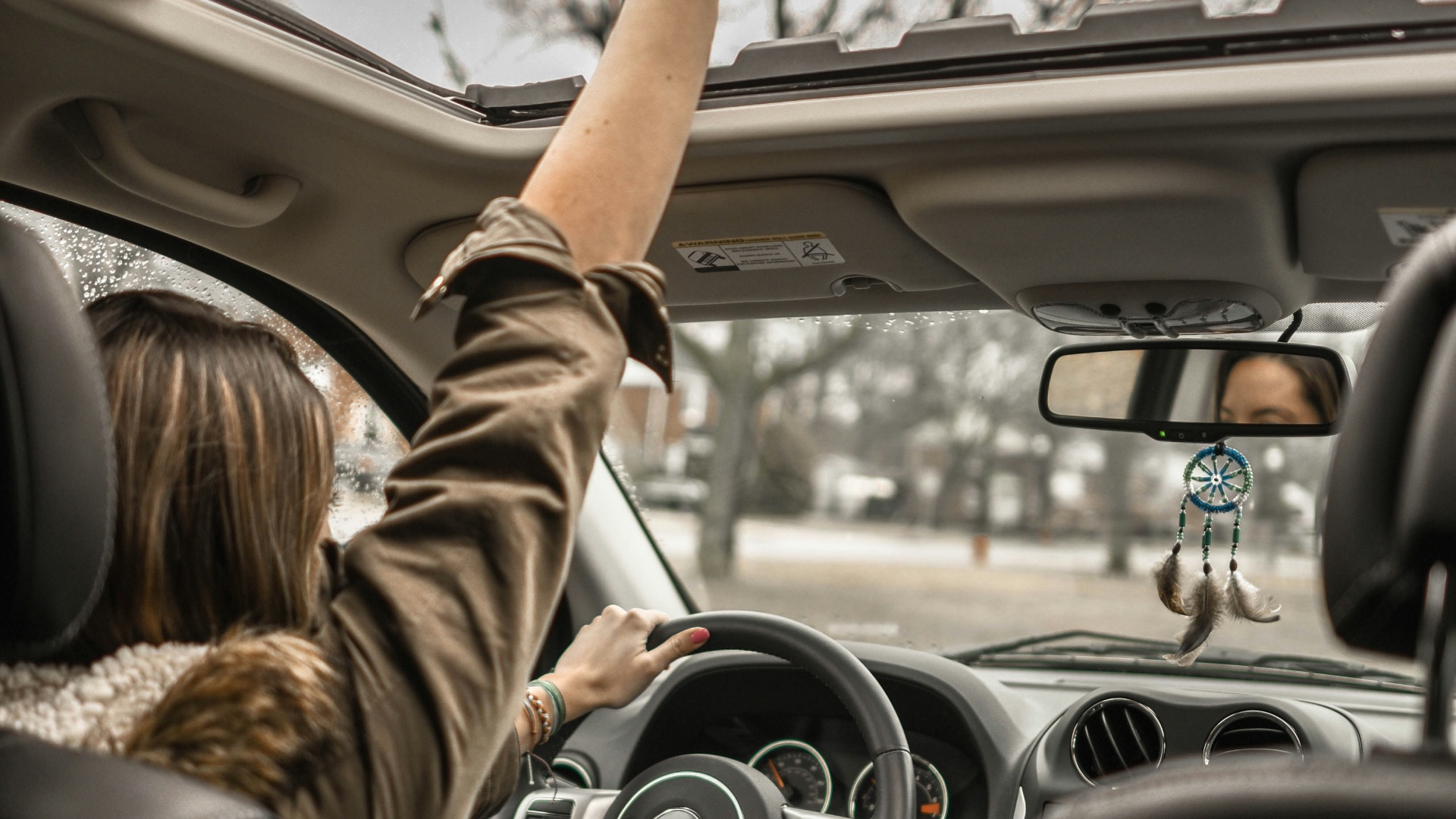 woman raising her right hand inside black and brown vehicle