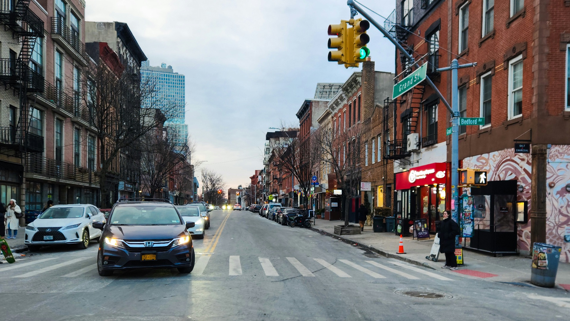 A city street filled with traffic next to tall buildings