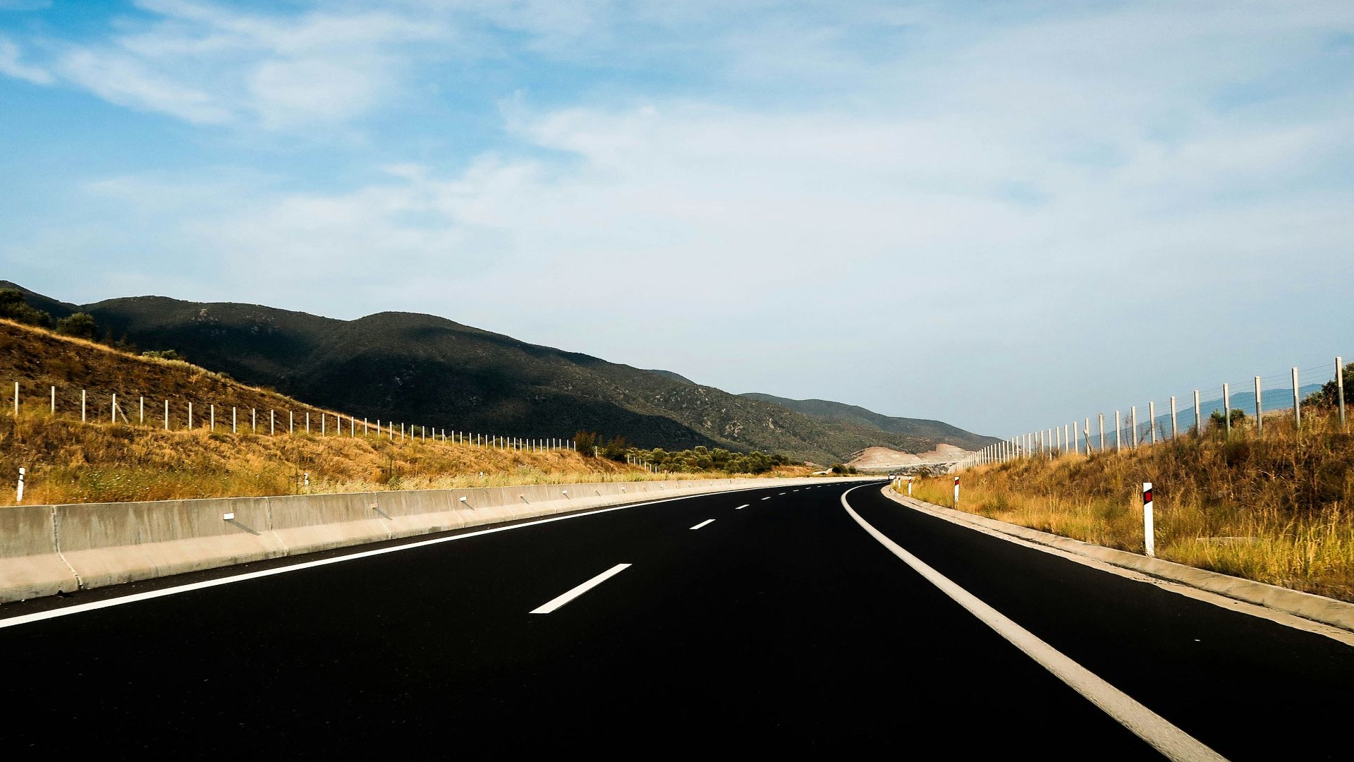 mountain ranges near road under cloudy sky