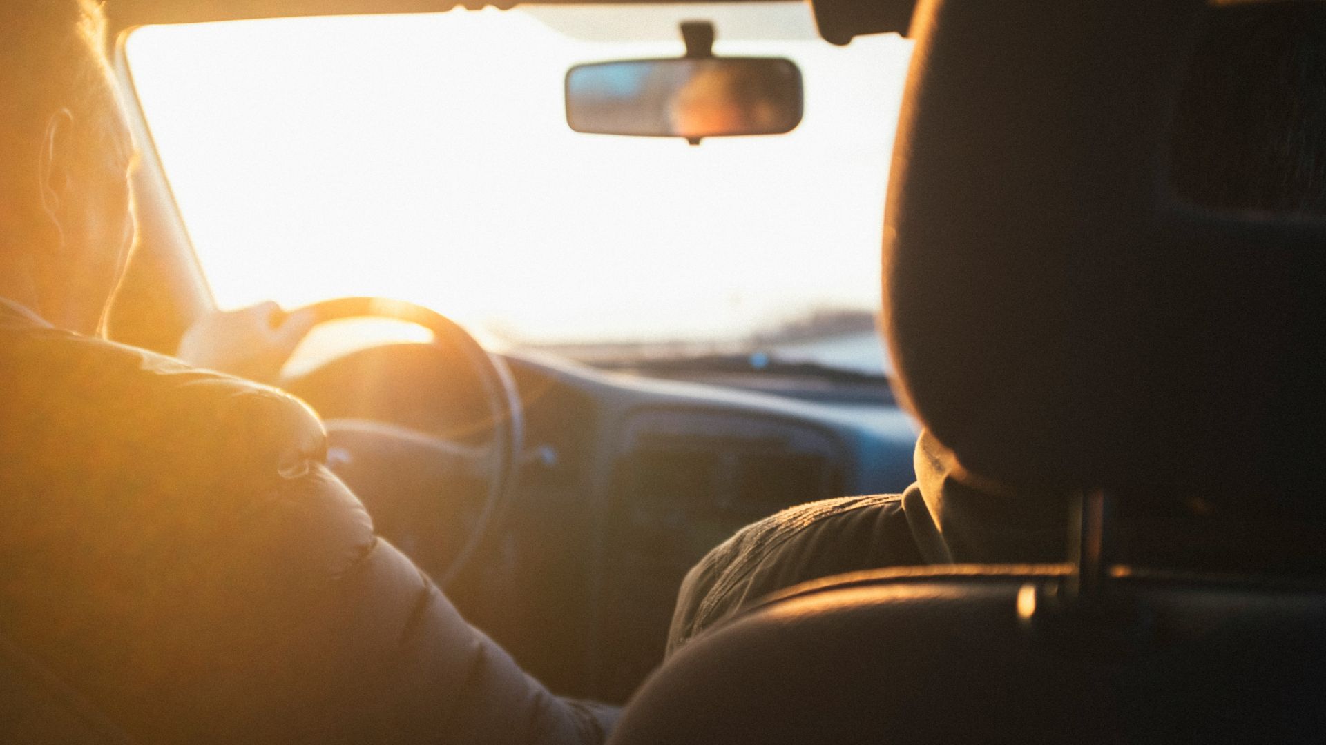 man driving car during golden hour