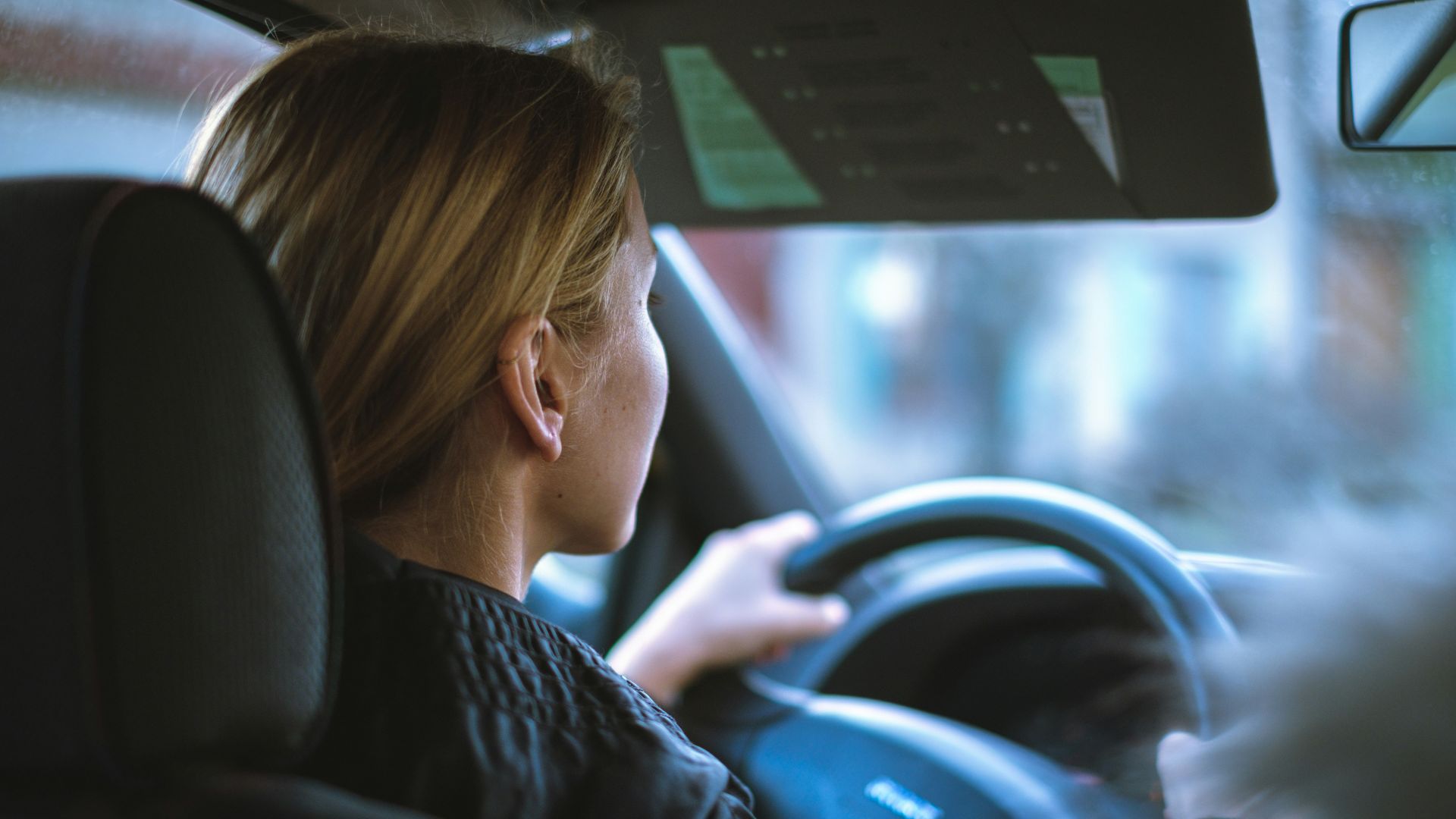 a woman sitting in a car with a steering wheel