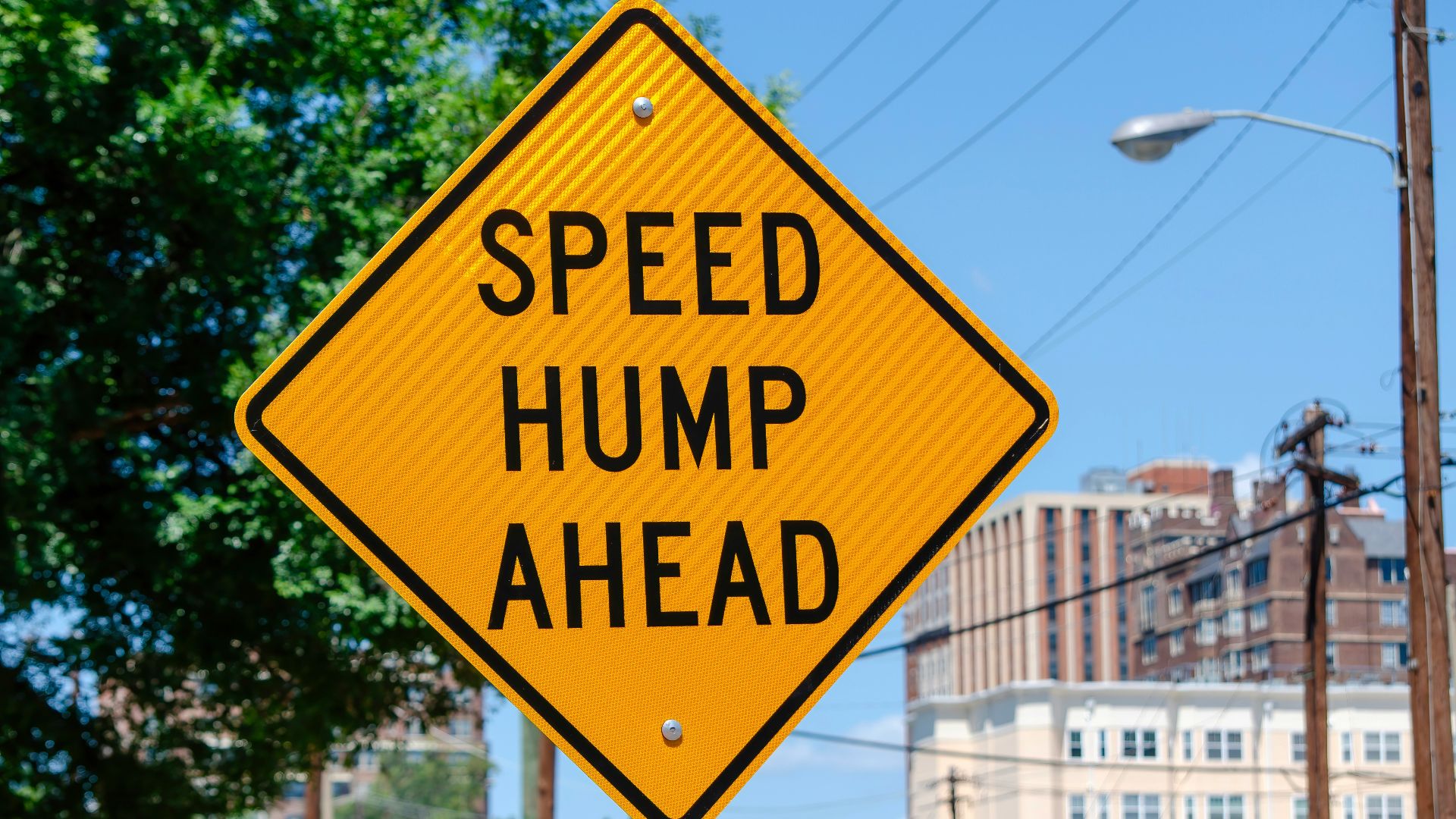 a yellow speed hump sign sitting on the side of a road