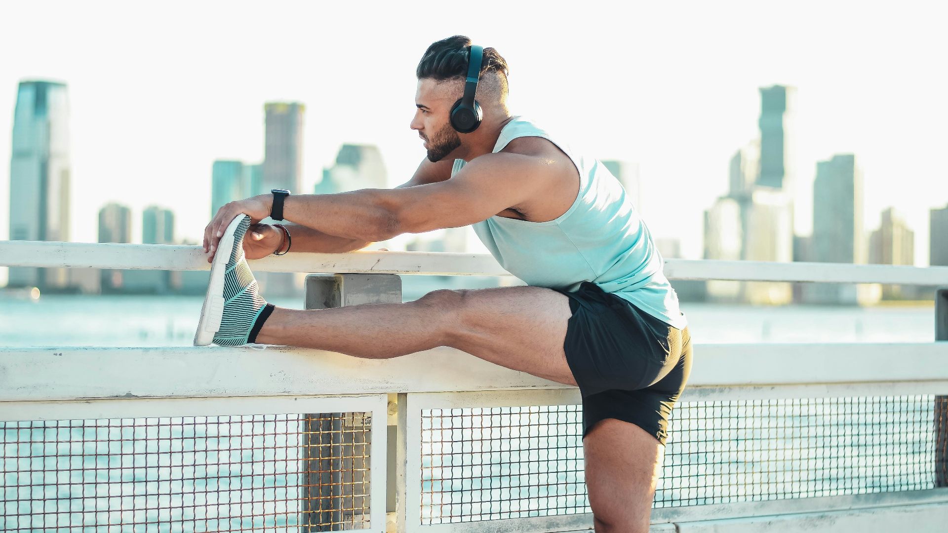 man in white tank top and black shorts doing push up during daytime