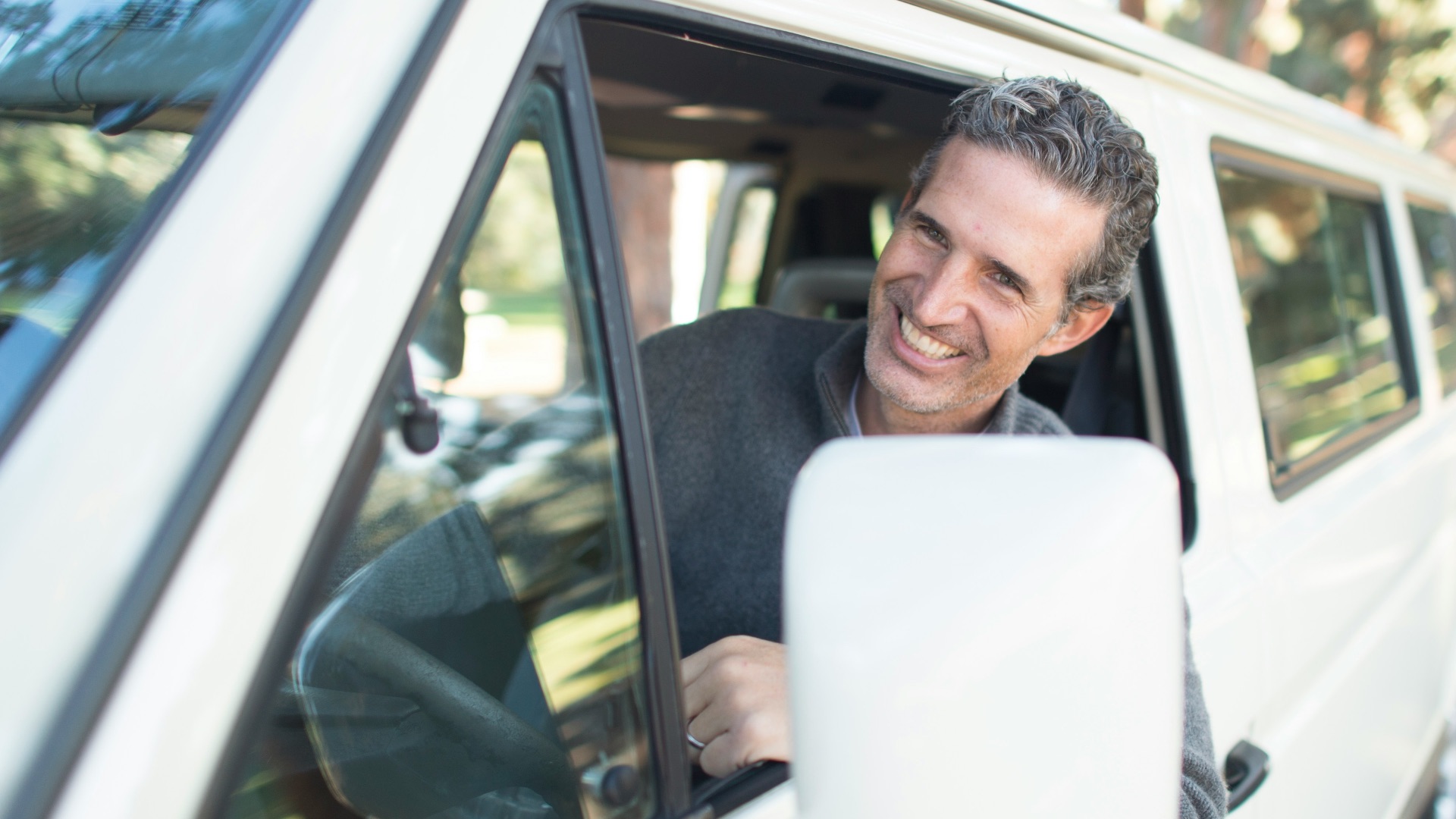 man in gray sweater leaning on van window