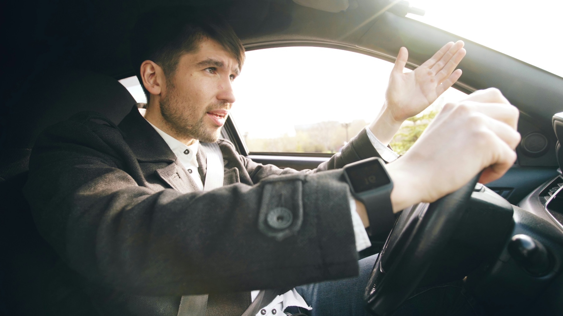 Man driving a car, gesturing with hand.