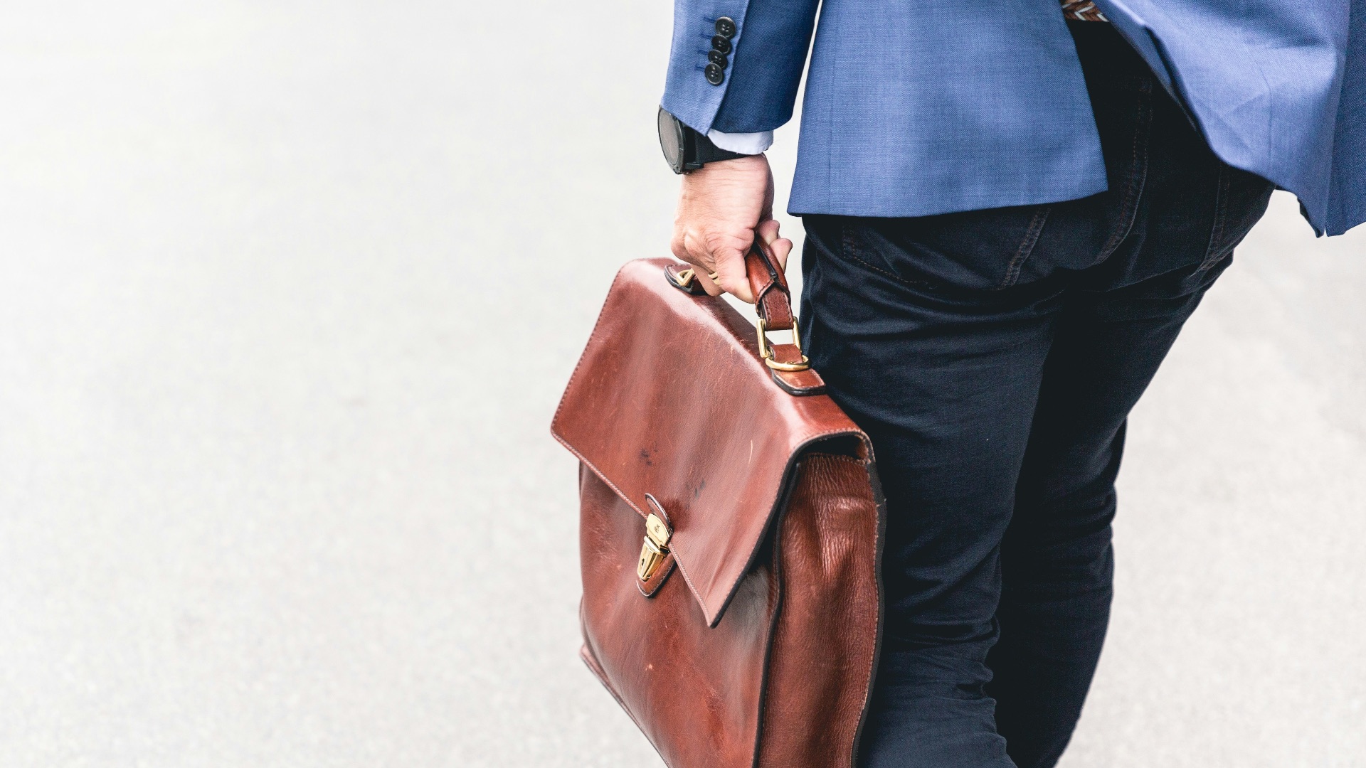 person walking holding brown leather bag