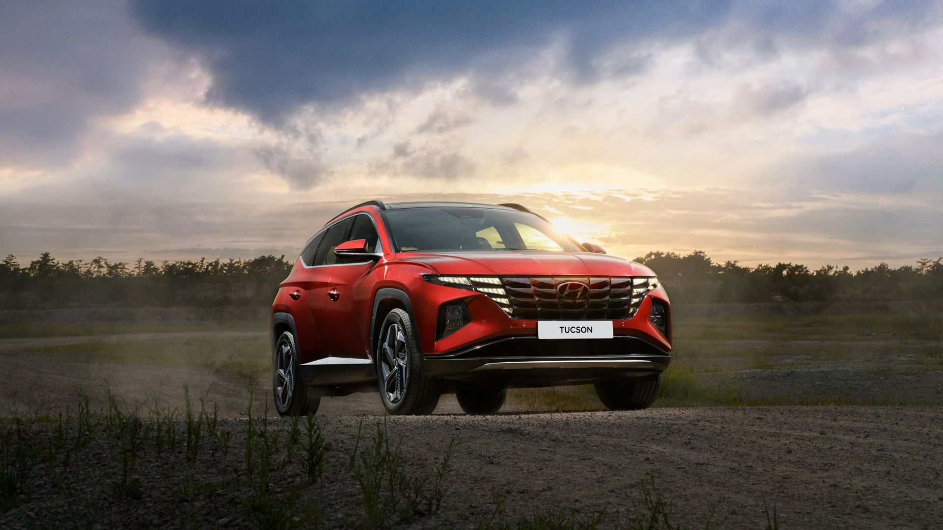 a red suv driving down a dirt road