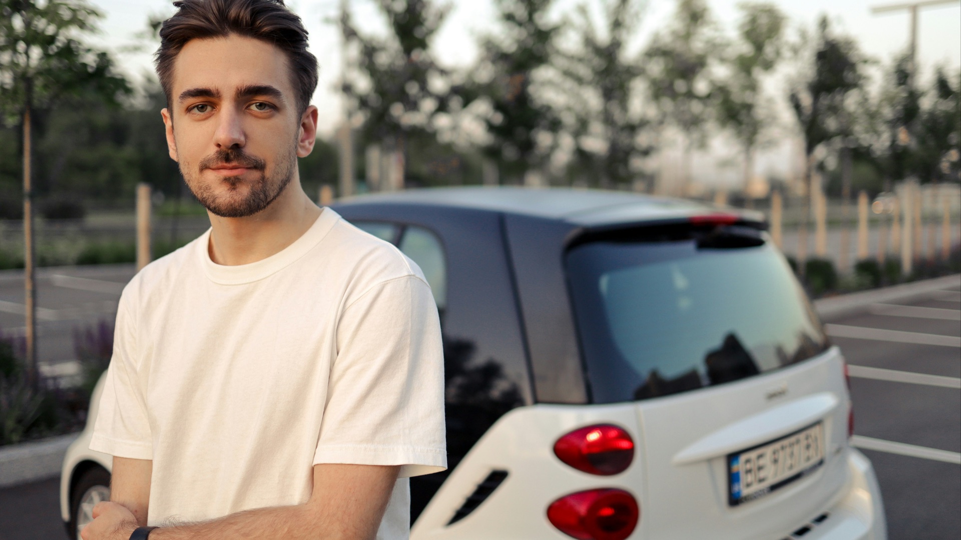 man in white crew neck t-shirt standing beside white car during daytime