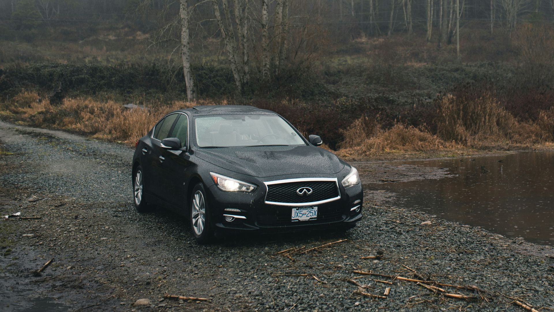 black sedan parked beside body of water during daytime