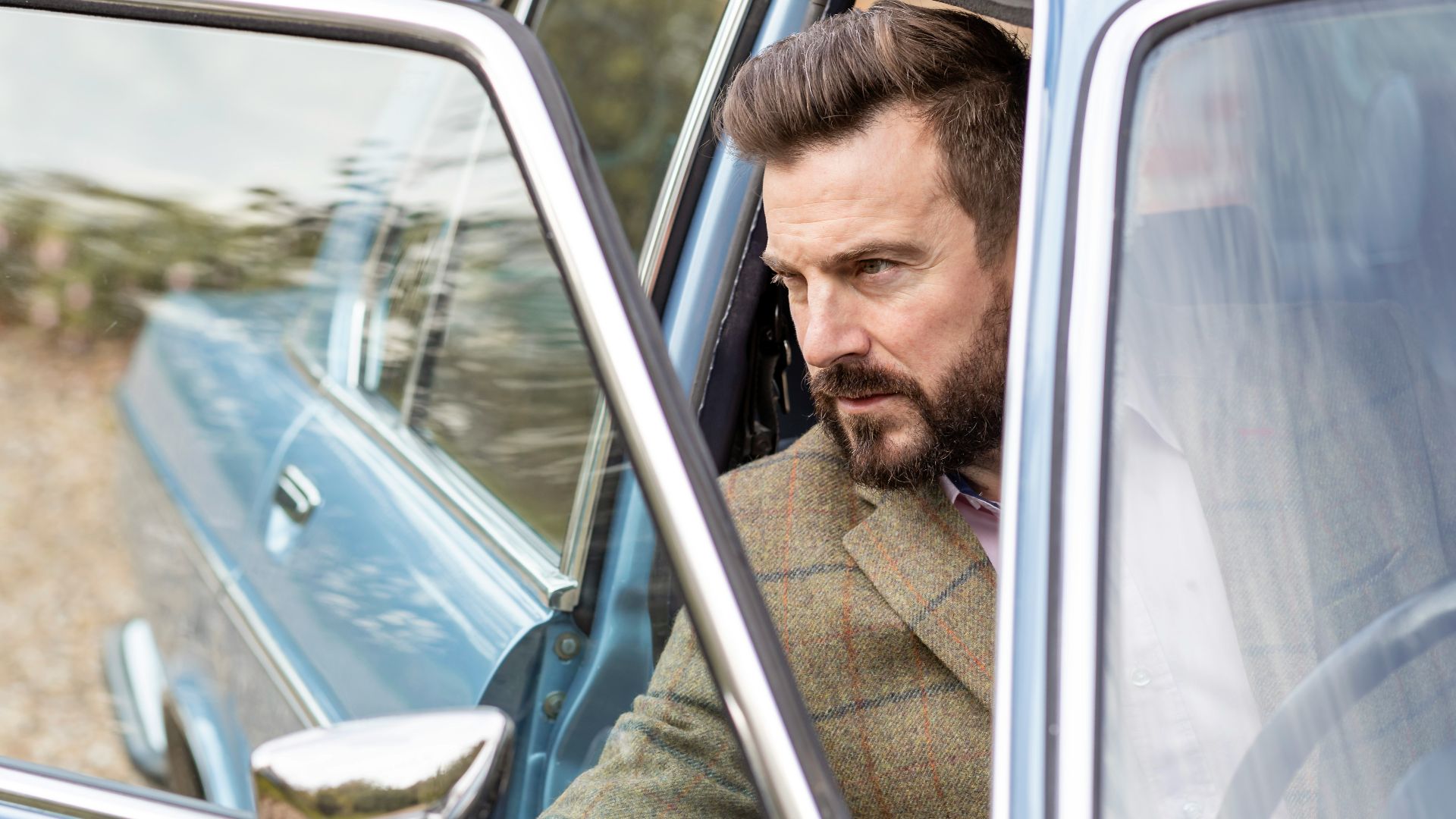 a man sitting in a car looking out the window