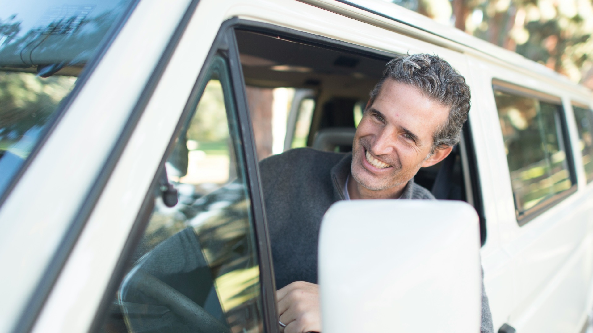 man in gray sweater leaning on van window