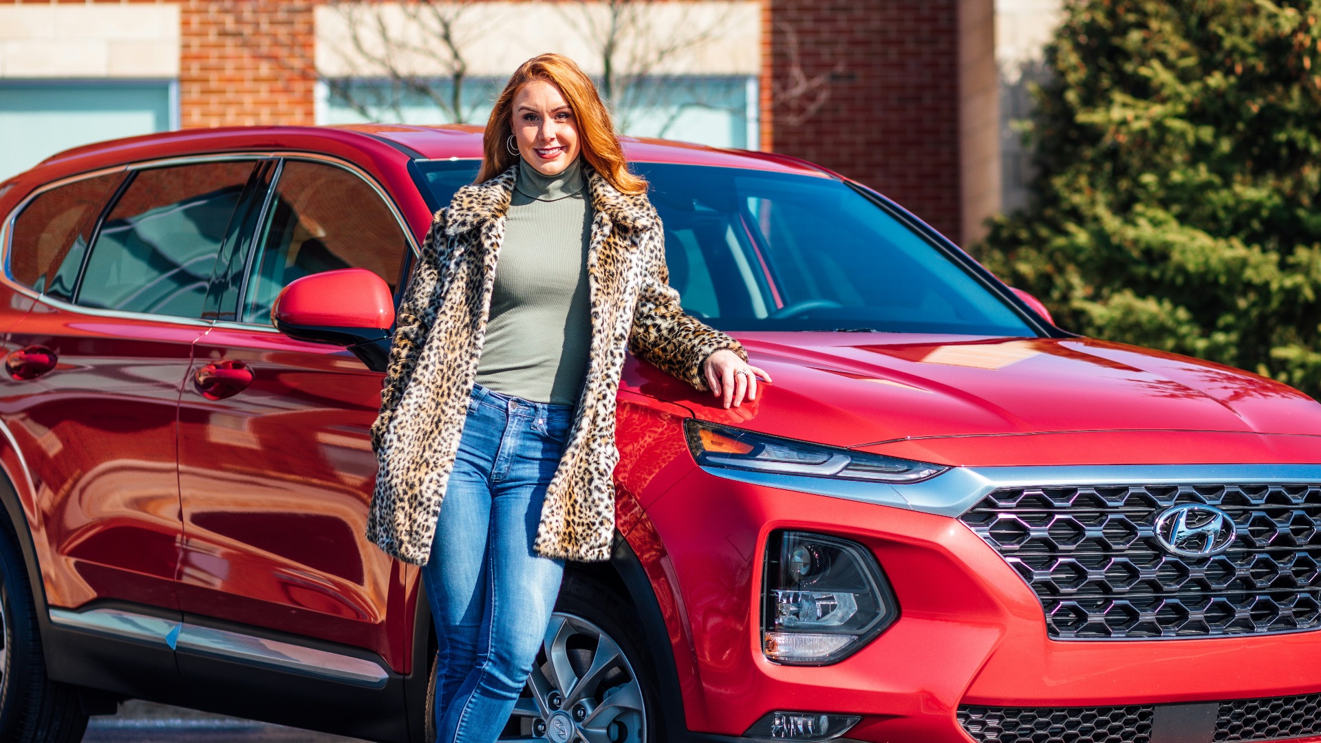 woman in white and black scarf and blue denim jeans standing beside red mercedes benz car