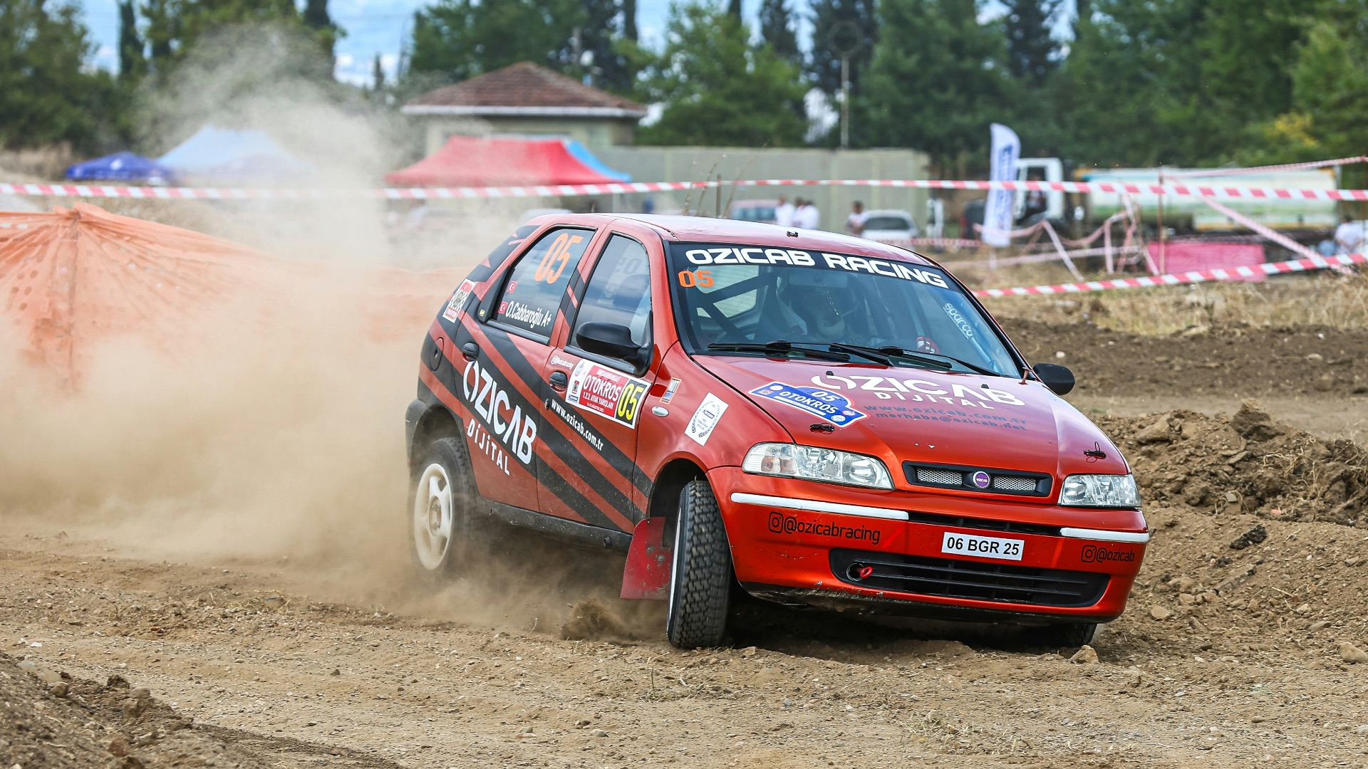 a red car driving down a dirt road