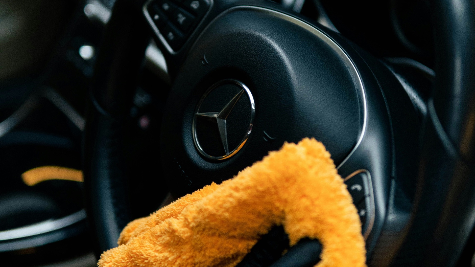 A person cleaning a car with a yellow cloth