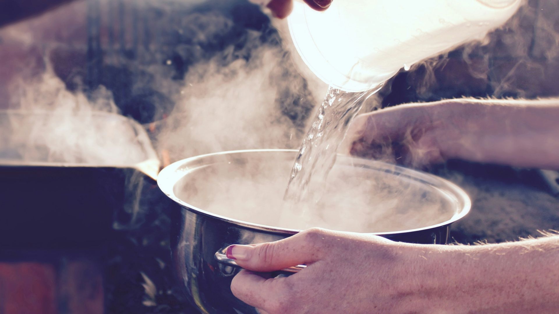 person pouring water on white ceramic mug