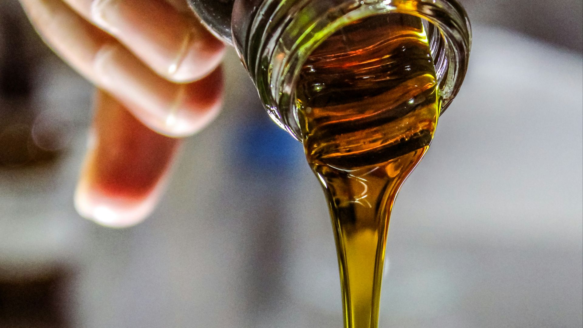 person holding clear drinking glass with brown liquid