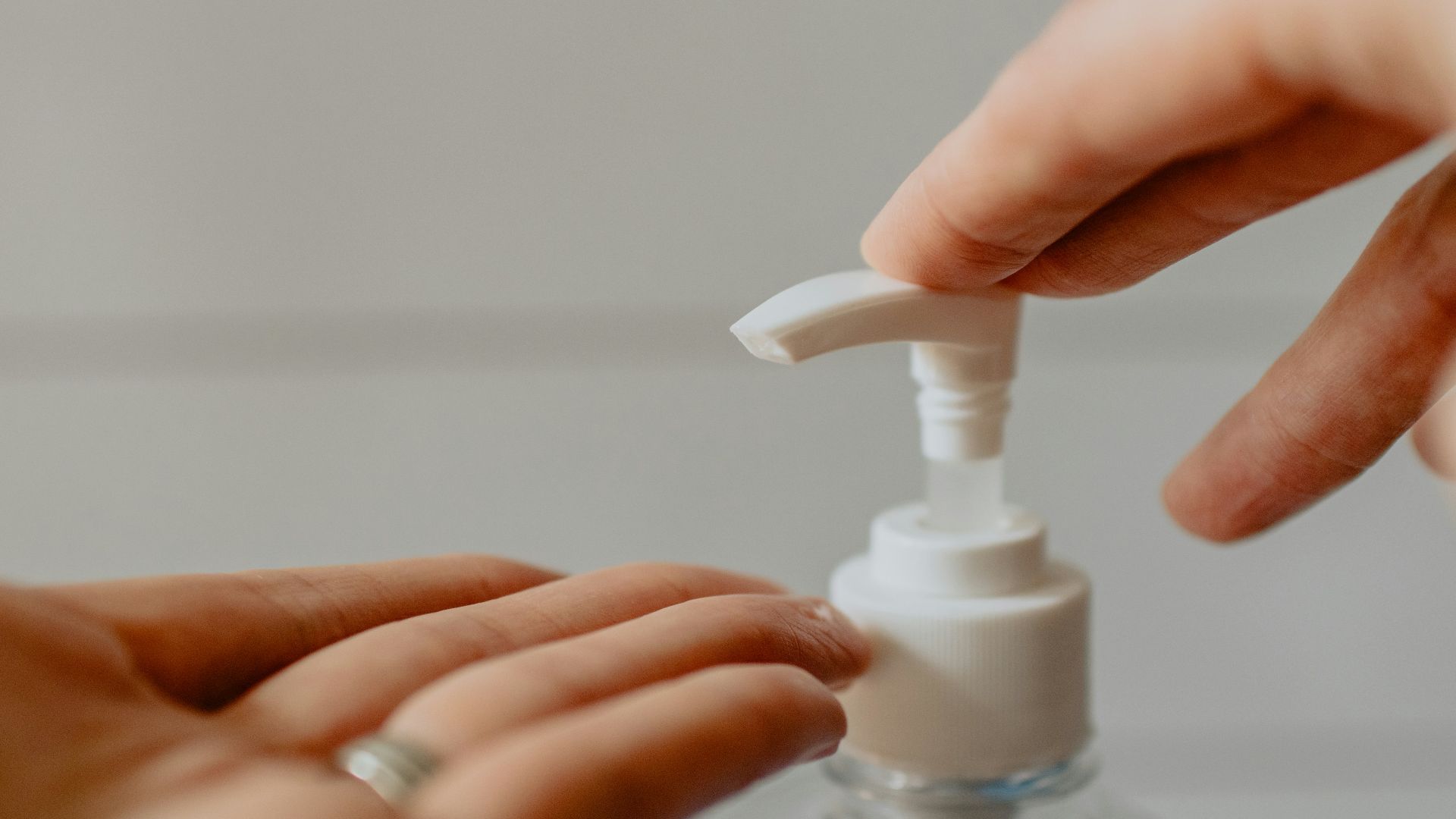 person holding white plastic pump bottle