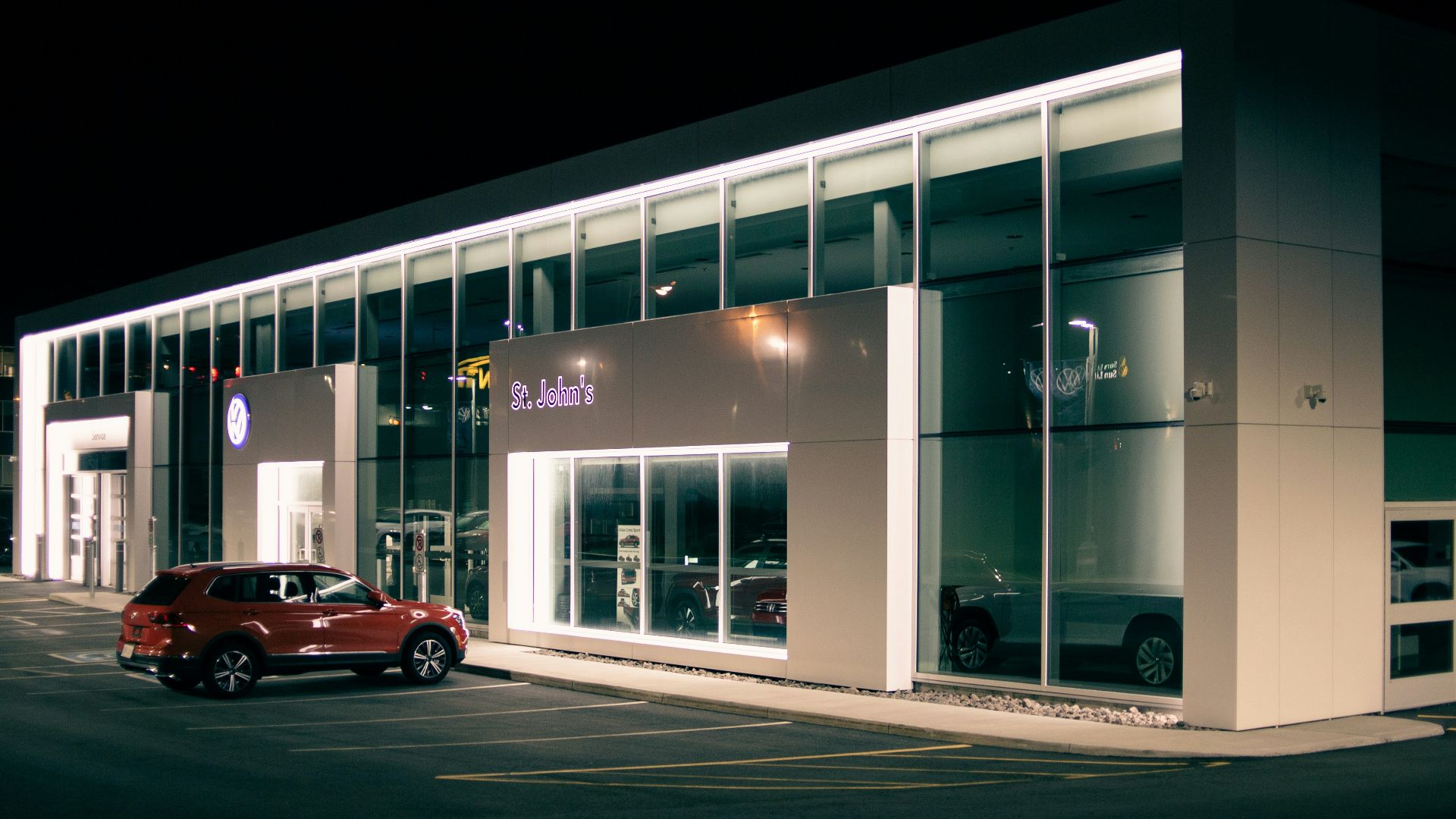 red car parked in front of white building during night time