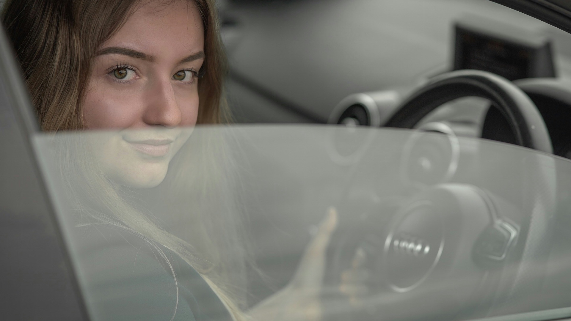 a woman sitting in a car holding a steering wheel