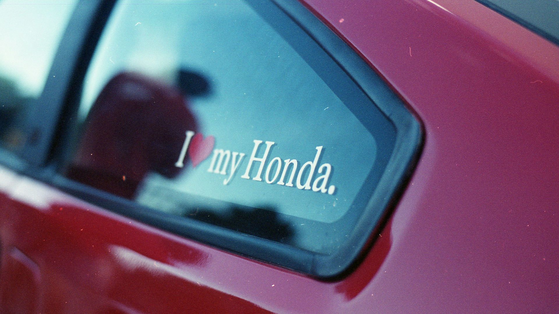 A red car with a sticker that says, i my honda