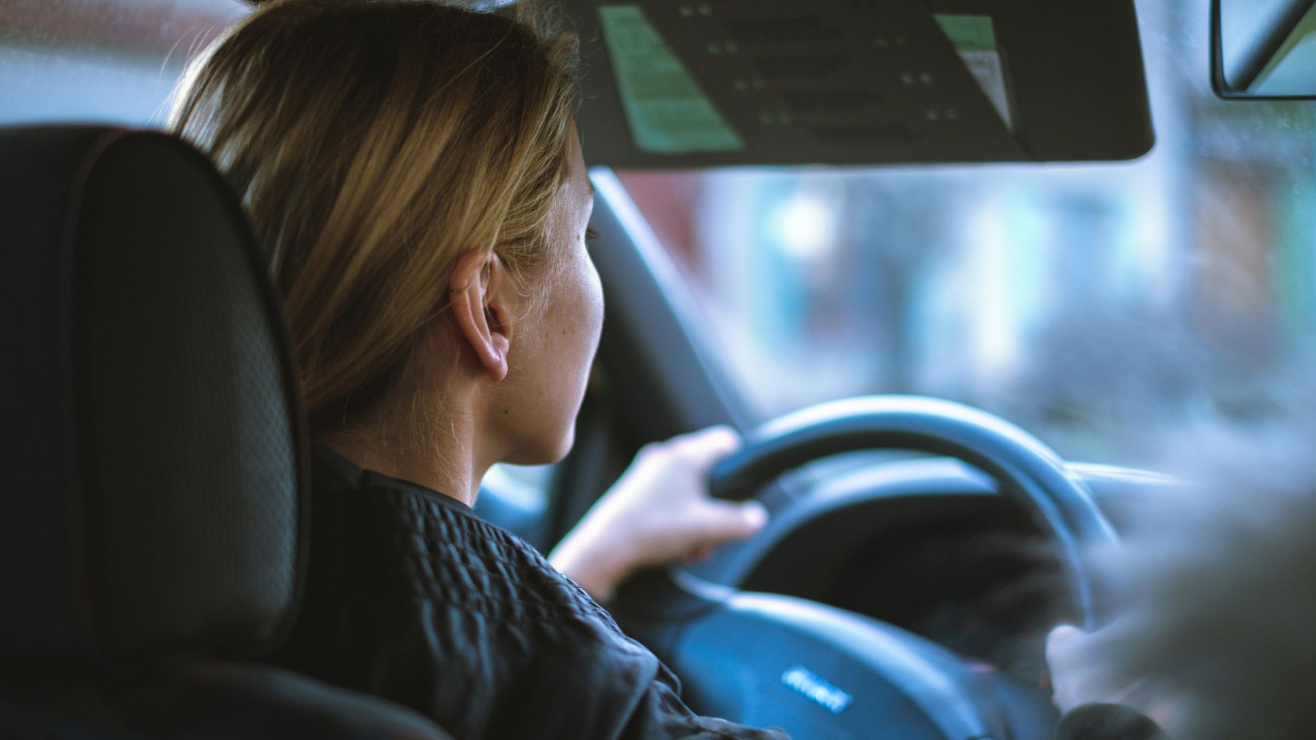 a woman sitting in a car with a steering wheel