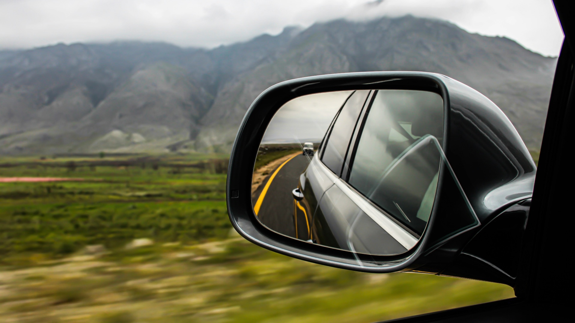 view of vehicle side mirror with vehicle at the back