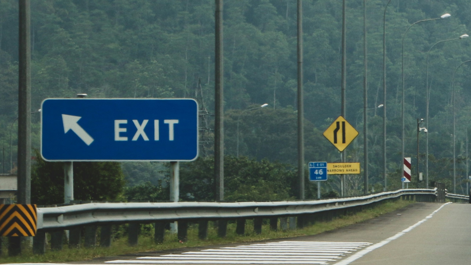 a truck driving down a highway next to a forest