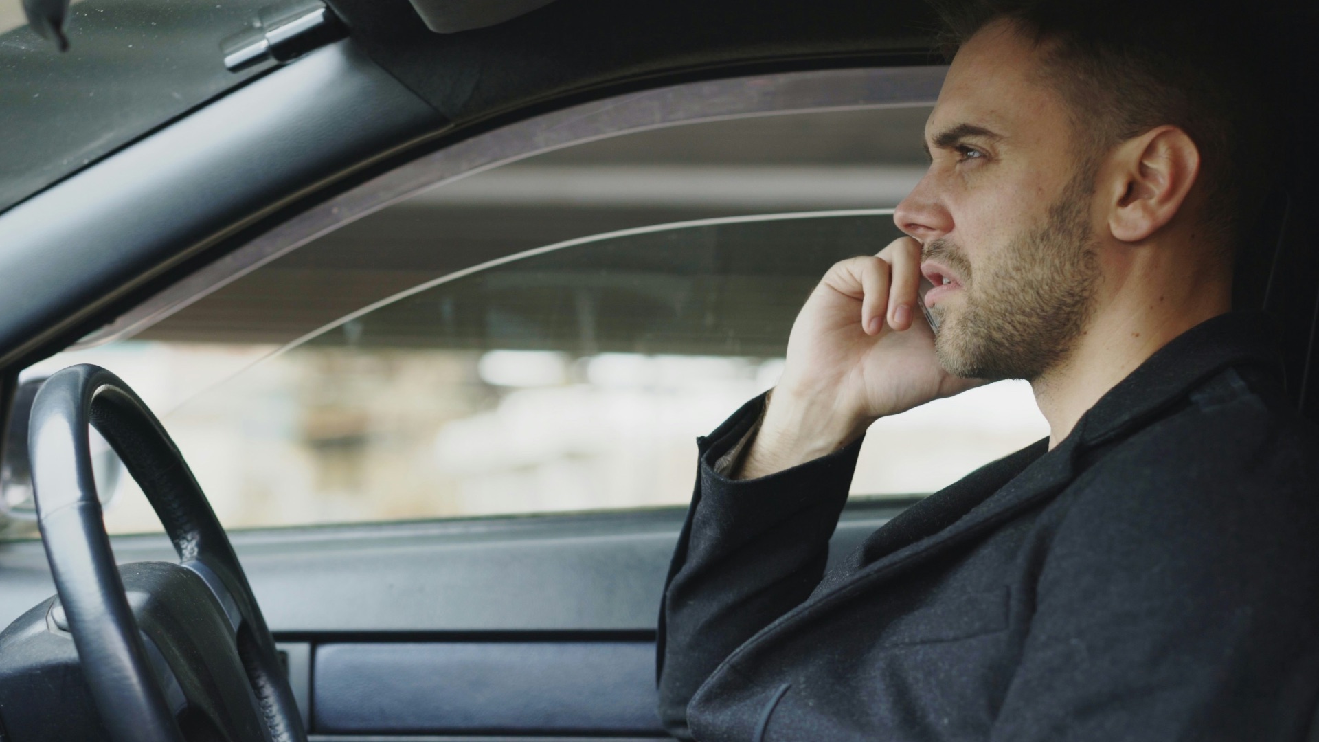 Man in suit talking on phone inside car