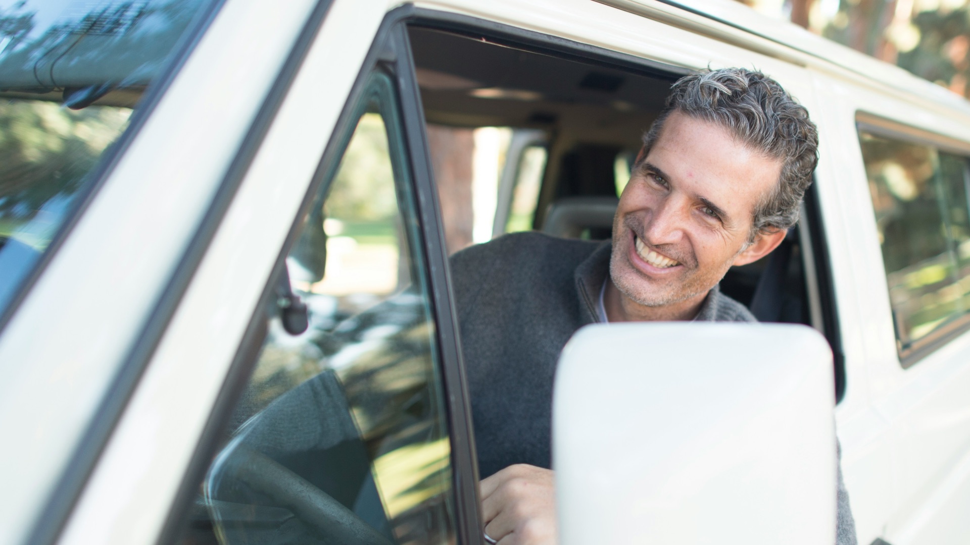 man in gray sweater leaning on van window