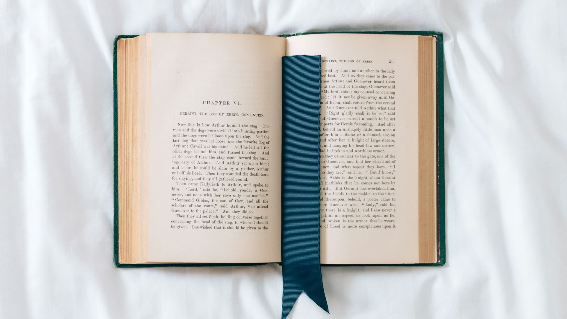 an open book with a blue ribbon on a white sheet