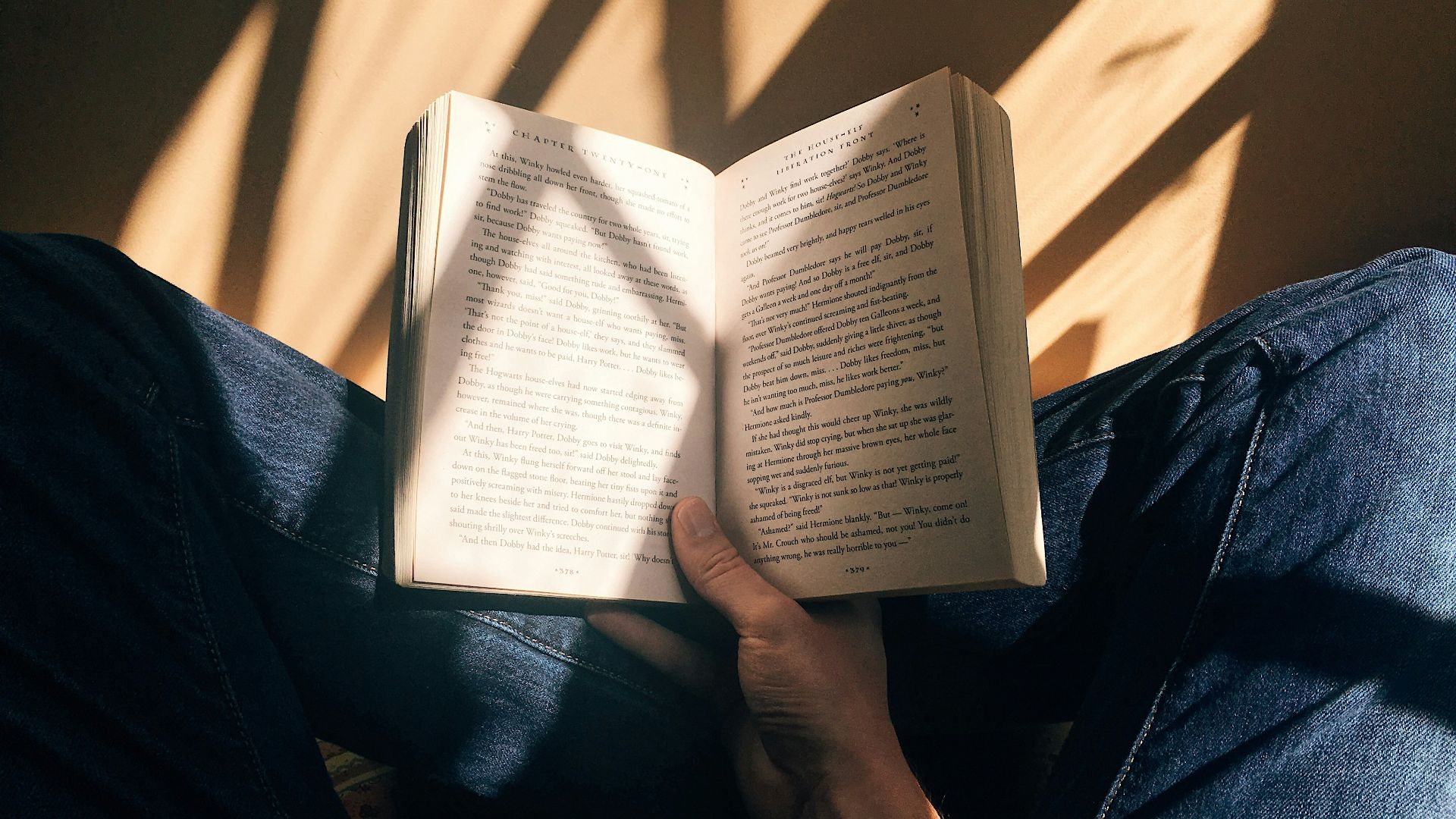person holding book sitting on brown surface