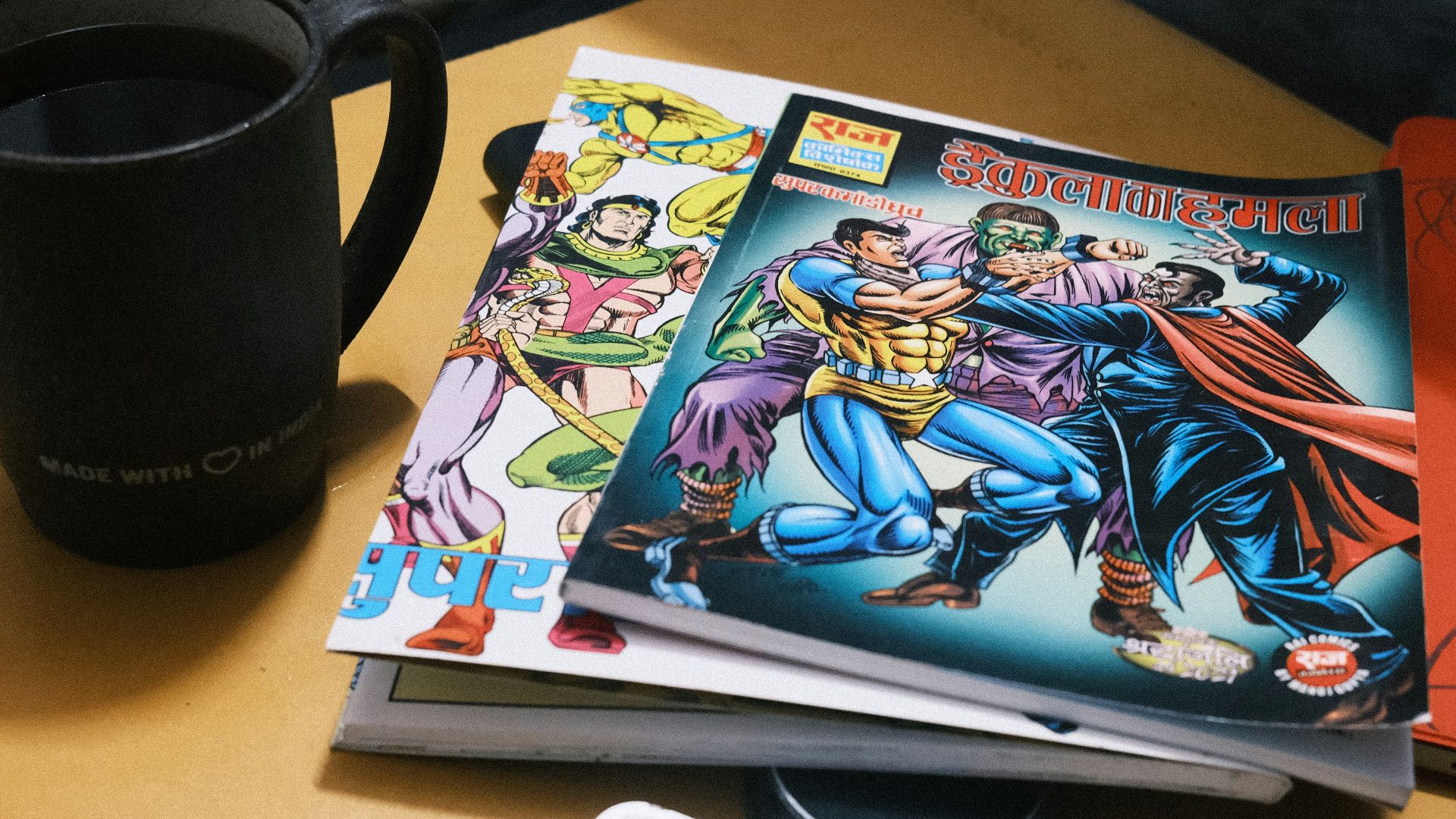 Stack of comic books next to a mug of coffee.