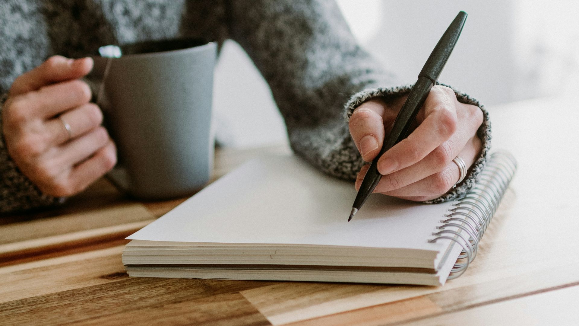 a woman sitting at a table writing on a notebook