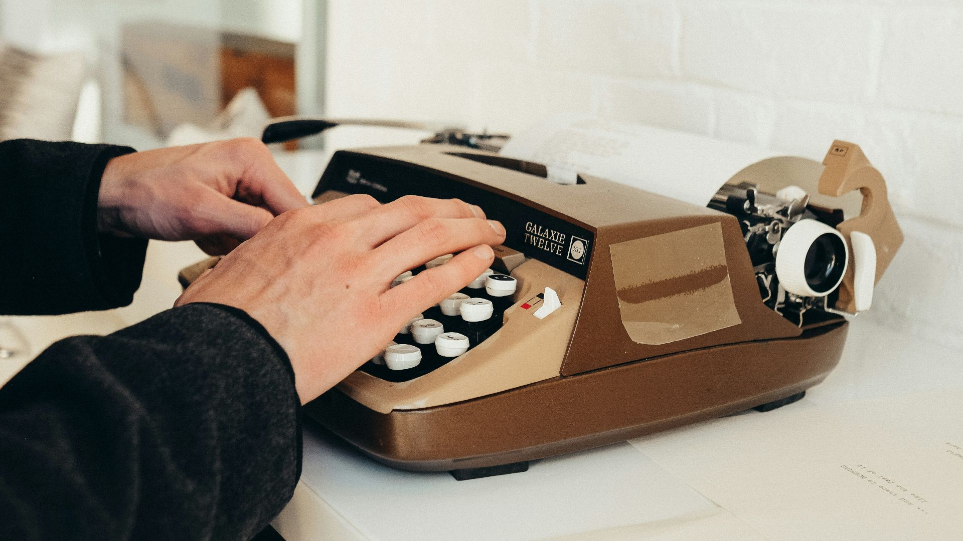 person in black long sleeve shirt using brown and white rotary phone